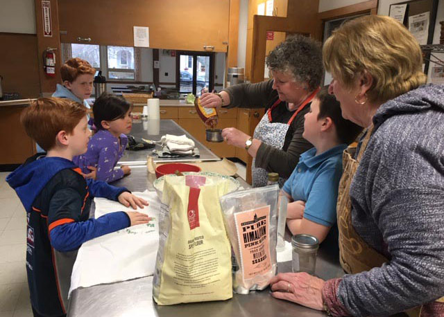 student gathered in a kitchen measuring ingredients to make bread